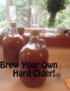 two brown jugs sitting on top of a counter next to a window with the words brew your own hard cider