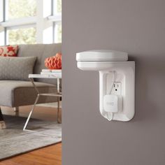 a white wall mounted device on the side of a gray wall in a living room