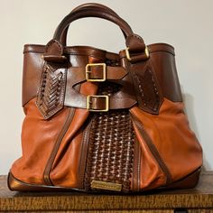 This Pre-Owned Burberry Bridle 2way Woven Accents Bag Is Guaranteed 100% Authentic, In Good Condition The Exterior Is Free Of Any Rips Or Cracks, There Are Very Few Scuffs And Scratches Throughout. The Corners And Pipping Are In Excellent Used Condition. The Leather Handles Show Minor Wear. The Zipper And Magnetic Closures Operate Properly And Runs Smoothly. The Hardware Shows Light Wear. The Interior Has No Stains And Features Two Magnetic Closure Sections And Multiple Zipper Pockets For Plenty Designer Cognac Satchel With Leather Handles, Luxury Leather Satchel For Errands, Luxury Cognac Leather Shoulder Bag For Errands, Luxury Cognac Shoulder Bag For Errands, Luxury Cognac Satchel For Errands, Burberry Purse, Show Lights, Leather Handles, 2 Way