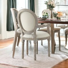 a dining room table with white chairs and a rug on the floor in front of it