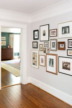 a living room with pictures on the wall and hardwood floors in front of it's doors