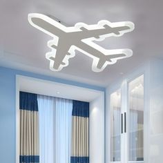 an airplane is flying in the sky above a bed and desk with blue curtains on it