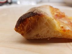 a piece of pizza sitting on top of a wooden cutting board