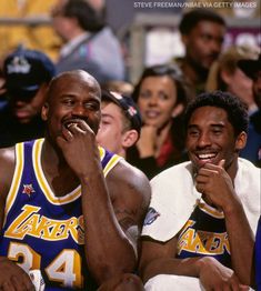 two lakers players sitting next to each other in front of a crowd with their hands on their mouths