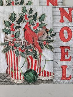 two christmas napkins with red birds and holly on them, one is for noel