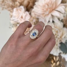 a woman's hand holding a ring with a blue and white diamond in it