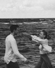 black and white photograph of two people walking on the beach