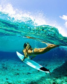 a woman is swimming in the ocean with her surfboard under water and she has long hair