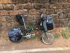 a bicycle parked next to a brick wall with a bag on the front and back