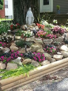 a garden with rocks and flowers in front of a house