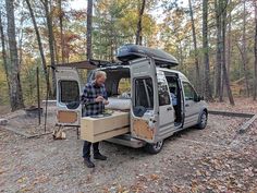 a man standing next to a van in the woods