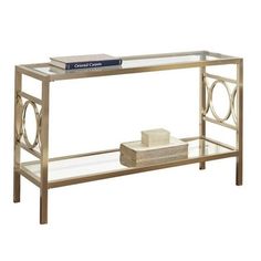 a glass and metal console table with a book on the bottom shelf next to it