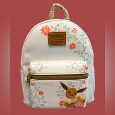 a white backpack with a pokemon print on it and flowers around the front pocket, along with a brown leather strap