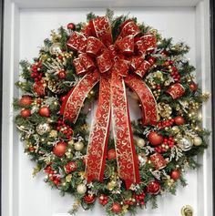 a christmas wreath with red and gold ornaments hanging on the front door, framed in a black frame