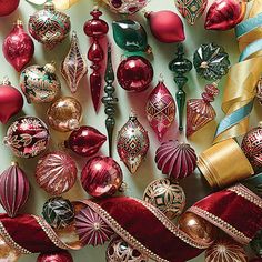 red and gold christmas ornaments are arranged on a white surface with ribbons, bows, and decorations