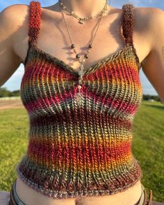 a close up of a person wearing a tank top and some necklaces on their neck