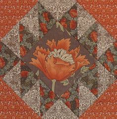 an orange and white flower is in the center of a quilted design on red fabric