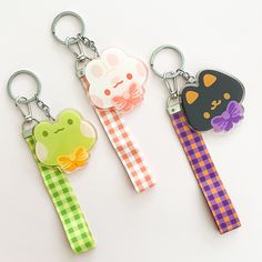 three key chains with different designs on them, one has a cat and the other is a frog