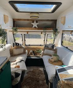 the inside of a camper with couches, pillows and plants on the windowsill