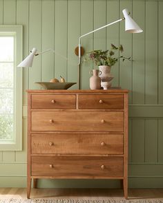 a wooden dresser with two lamps on top of it