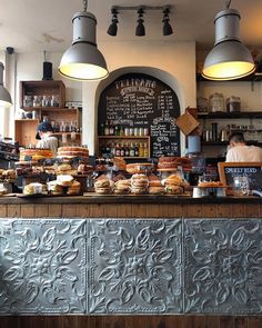 a counter with lots of pastries on it and hanging lights above the bar area