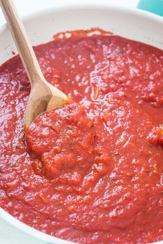 a white bowl filled with sauce and a wooden spoon