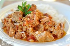 a close up of a plate of food with rice and meat in sauce on it