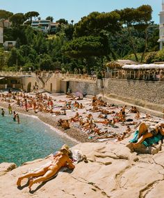 many people are laying on the rocks near the water and in the sun at the beach