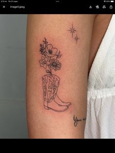 a woman's arm with a tattoo on it and flowers in a cowboy boot