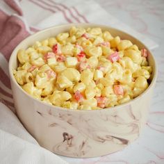 a white bowl filled with macaroni and cheese on top of a pink towel