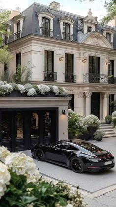 a black sports car parked in front of a large white building with lots of windows