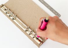 a person writing on a piece of paper with a pink pen in front of it