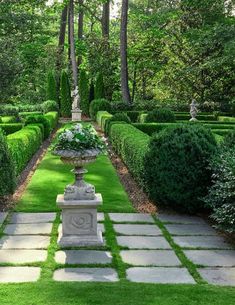 a garden with green grass and stone walkways leading to the topiary, surrounded by trees