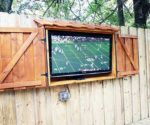 a large screen mounted to the side of a wooden fence