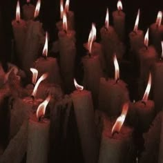 many lit candles are lined up in rows