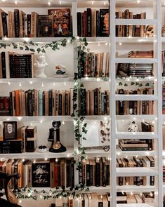 a bookshelf filled with lots of books next to a white wall covered in lights