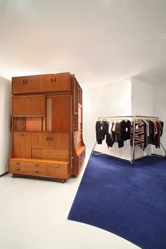 an empty room with clothes on racks and a blue carpet in front of the closet