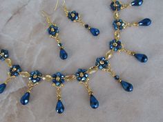 a necklace and earring set with blue glass beads on a piece of paper that is laying on the ground