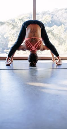 a woman is doing yoga in front of a window with her hands behind her head