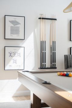 a pool table with cues and cues in front of some pictures on the wall