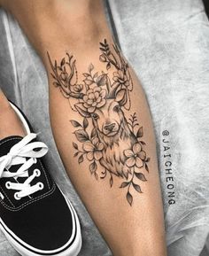 a woman's leg with a deer and flowers tattoo on it