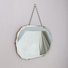 a mirror hanging on the wall with a chain around it