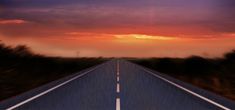 the sun is setting over an empty road with trees on both sides and dark clouds in the background