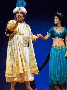 two people dressed in costumes on stage with one holding the hand of another person's hand