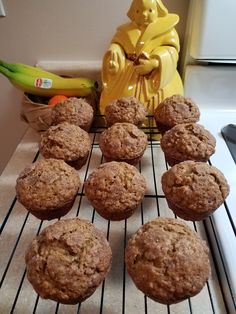 muffins cooling on a rack in front of a buddha statue and some bananas