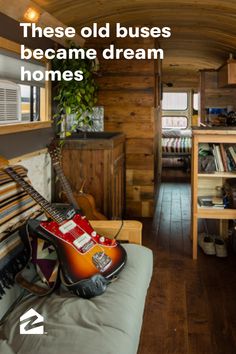 there is a guitar sitting on the couch in this tiny room with wood paneling