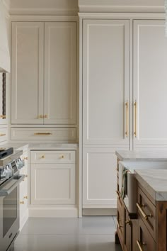 a kitchen with white cabinets and gold pulls on the doors, drawers, and counter tops