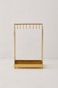 a gold metal rack with clothes hanging on the side and two pegs attached to it