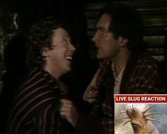 two men laughing together in the dark with an advertisement behind them that says live slug reaction