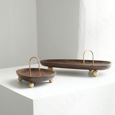 two wooden trays sitting on top of a white table next to each other with gold handles